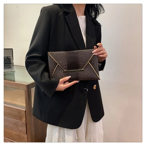 Detail of dark brown crocodile pattern envelope clutch with golden metal clasp