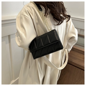 Close-up of black quilted crossbody bag with gold chain strap on a model back