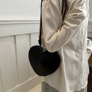 Fashionable black heart-shaped crossbody bag with silver zipper and thin shoulder strap