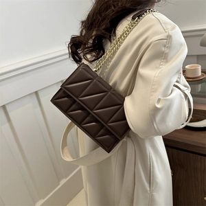 Brown quilted crossbody bag with golden chain strap on a model back for chic style