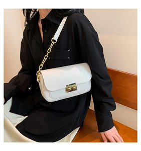 Detailed view of white leather crossbody bag with gold chain strap and metal lock buckle