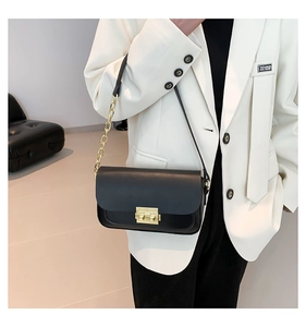 Detail of black flap shoulder bag with gold metal buckle and chunky chain strap