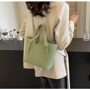 Pistachio green PU leather tote bag with gold hardware shown on a model's shoulder