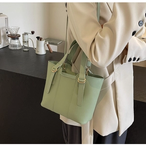 Detail of mint green tote bag featuring golden metal buckles and adjustable strap