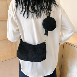 Chic black corduroy crescent crossbody bag with mini pouch shown on a model