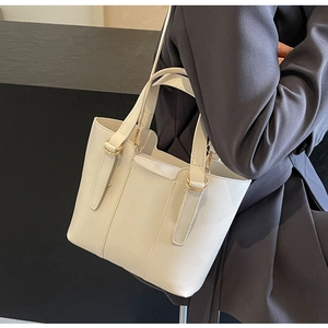 Detail of white ivory tote bag with minimalist gold ring hardware and leather texture