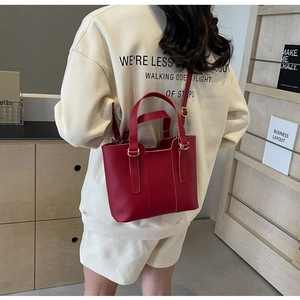 Detail of red leather tote bag with golden metal rings and adjustable shoulder strap