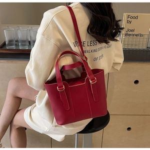 Détail du sac cabas rouge en cuir avec bandoulière réglable et boucles dorées