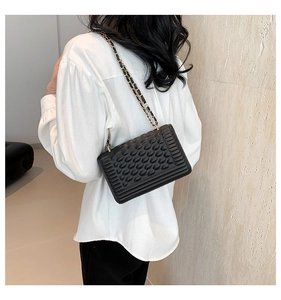 Detail of black chain square bag featuring textured pattern and metallic chain strap