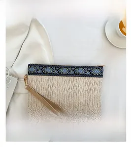 Detailed view of bohemian straw woven clutch with floral embroidery and PU wristlet