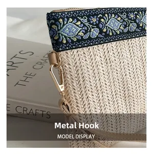 Detail of floral embroidery and gold metal clasp on woven straw clutch bag