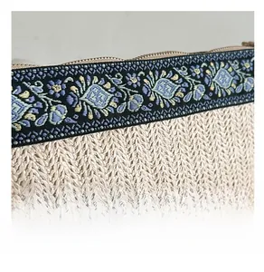 Detail of hand-woven straw bag featuring colorful floral embroidery and metal zipper closure
