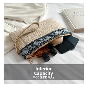 Detail view of ethnic straw clutch bag showing capacity for phone and cosmetics