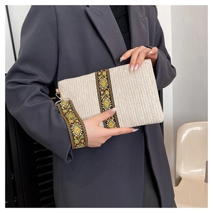 Detail of cream woven clutch with ethnic floral embroidery and golden metal hardware
