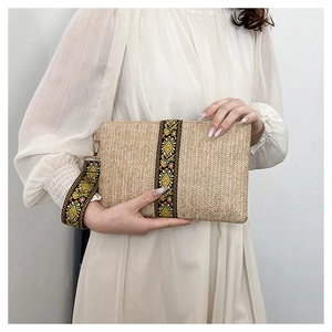 Close-up of a straw clutch with ethnic floral embroidery and gold metal zipper hardware