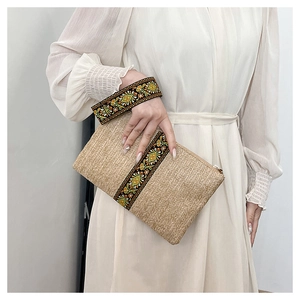 Detail of handwoven straw clutch with intricate ethnic embroidery and secure zipper closure