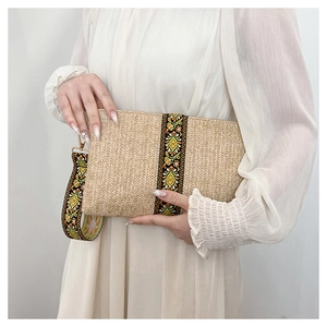 Detailed shot of ethnic floral embroidery and straw texture on a summer beach clutch bag