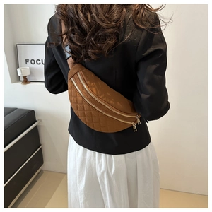 Detailed back view of a brown quilted chest bag with dual gold zippers on a model