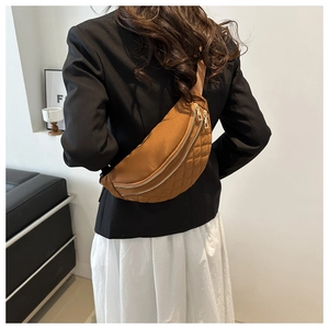 Brown quilted crossbody chest bag shown on model with dual metal zippers and casual style