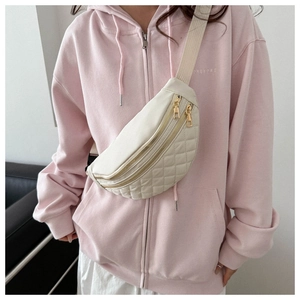 Detailed view of beige quilted crossbody bag with gold zippers and wide strap