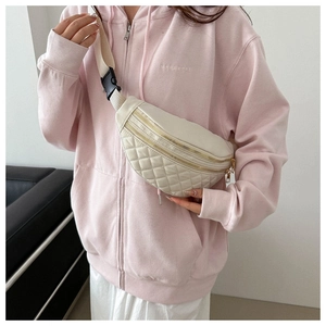Close-up of beige quilted fanny pack showing dual gold zippers and adjustable strap