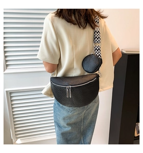 Close-up of black pebble leather saddle bag with geometric wide strap and mini coin purse