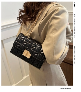 Detalle del bolso acolchado negro con hebilla dorada y cadena sobre un traje color beige