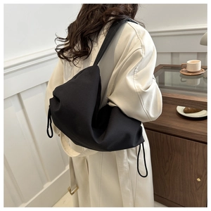 Detail of minimalist black canvas shoulder bag with drawstring showing capacity and soft texture