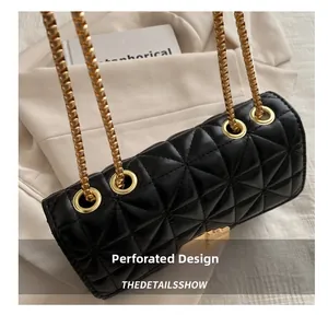 Detalle de bolso acolchado negro con ojales dorados y correa de cadena deslizante