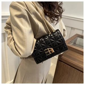 Primer plano de bolso acolchado negro con cadena dorada usado por una modelo