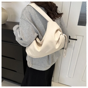 Detail of soft beige leather pleated shoulder bag with drawstring closure and wide strap