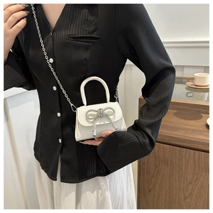 Détail du mini sac blanc pailleté avec nœud en cristal et bandoulière chaîne