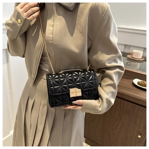 Bolso bandolera acolchado negro con cadena dorada lucido por modelo en interiores