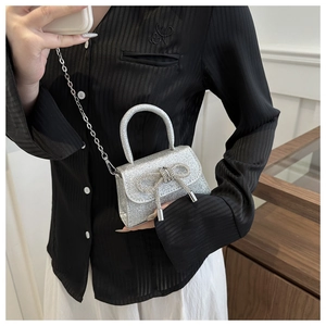 Close-up of silver mini handbag featuring a rhinestone bow and sparkly sequin texture