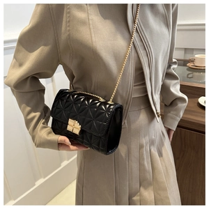 Detalle del bolso bandolera de cuero acolchado negro con cadena dorada y cierre metálico