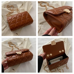 Detail view of brown quilted crossbody bag with gold chain strap and metal lock closure