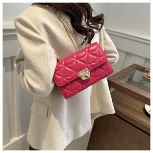 Detail of rose red quilted crossbody bag with gold chain strap and geometric metal lock