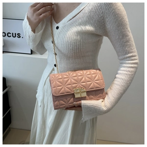 Detalle de bolso bandolera acolchado rosa con cadena dorada y cierre de presión cuadrado
