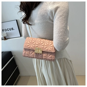 Detalle de bolso bandolera acolchado rosa con cadena dorada sobre suéter blanco