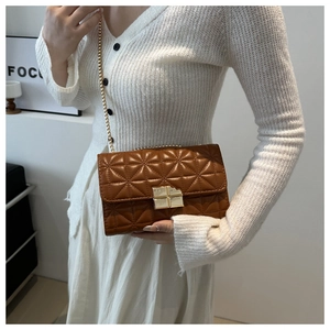 Bolso bandolera acolchado marrón con cadena dorada usado por una modelo
