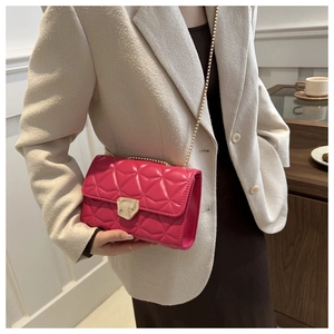 Detailed view of magenta quilted crossbody bag with gold chain and shield lock
