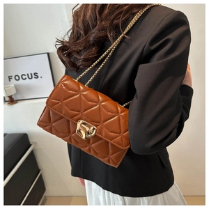 Detail of brown quilted chain bag featuring retro gold metal lock and leather texture
