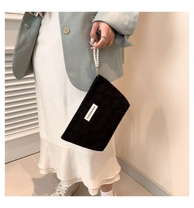 Detail of black mini pouch with heart embossed texture and elegant pearl wrist strap