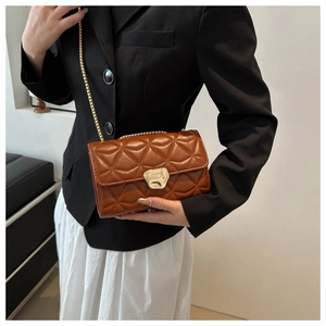 Detail of a brown quilted leather crossbody bag with a gold metal clasp and chain strap