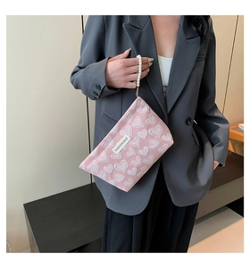 Pink canvas handbag featuring white heart jacquard patterns and elegant pearl strap details