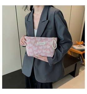 Pink heart-embossed mini phone bag featuring a luxury pearl handle and fashion label