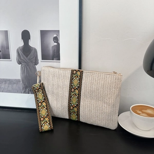 Chic straw woven clutch bag with floral embroidery detail and elegant wristlet strap