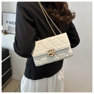 Close-up of white quilted chain bag with elegant gold hardware on a stylish model