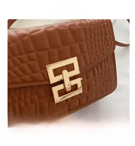 Detail of crocodile embossed brown handbag with golden geometric lock and vintage texture