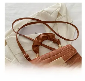 Detail of brown crocodile pattern handbag featuring a gold double E lock and pleated handle